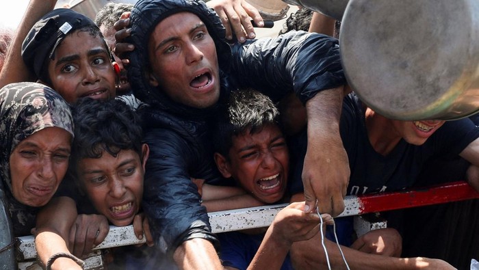 Palestinians react as they wait to receive food from a charity kitchen, amid a hunger crisis, in Gaza City, July 26, 2025. REUTERS/Mahmoud Issa     TPX IMAGES OF THE DAY