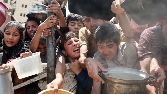 Palestinians wait to receive food from a charity kitchen, amid a hunger crisis, in Gaza City, July 28, 2025. REUTERS/Khamis Al-Rifi