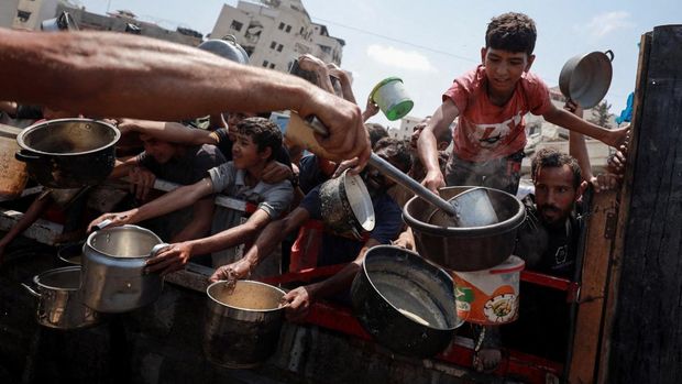 Palestinians wait to receive food from a charity kitchen, amid a hunger crisis, in Gaza City, July 28, 2025. REUTERS/Khamis Al-Rifi