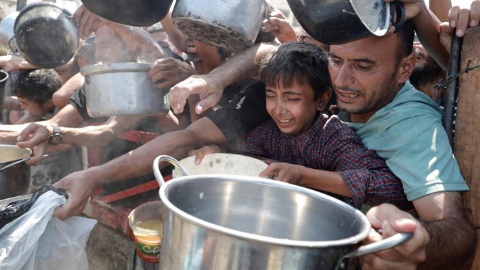 Palestinians wait to receive food from a charity kitchen, amid a hunger crisis, in Gaza City, July 28, 2025. REUTERS/Khamis Al-Rifi