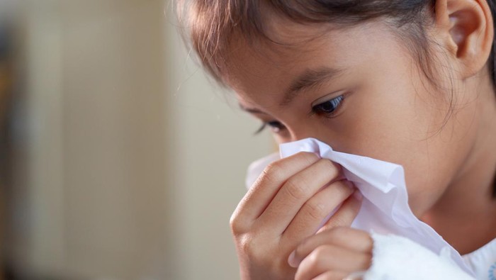Sick asian child girl wiping and cleaning nose with tissue on her hand in the hospital