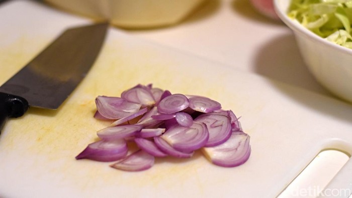 Closeup red onion slice and knife on cutting board.
