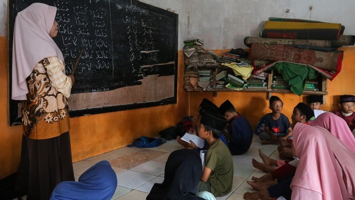 Sejumlah siswa mengikuti kegiatan belajar mengajar tanpa meja dan kursi di Madrasah Diniyah Takmiliyah Awaliyah (MDTA) Hidayatul Mubtadi’in, Pulosari, Kabupaten Pandeglang, Banten, Rabu (30/7/2025). Menurut pihak madrasah yang berlokasi di kaki Gunung Pulosari dan didirikan tahun 2007 serta memiliki murid sebanyak 70 orang itu belum bisa melengkapi fasilitas meja dan kursi untuk siswa karena kekurangan anggaran, sementara tenaga pengajarnya dibayar secara sukarela oleh orang tua murid dan hanya mendapatkan dana hibah rata-rata Rp5 juta per tahun. ANTARA FOTO/Angga Budhiyanto/tom.