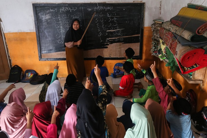 Sejumlah siswa mengikuti kegiatan belajar mengajar tanpa meja dan kursi di Madrasah Diniyah Takmiliyah Awaliyah (MDTA) Hidayatul Mubtadiin, Pulosari, Kabupaten Pandeglang, Banten, Rabu (30/7/2025). Menurut pihak madrasah yang berlokasi di kaki Gunung Pulosari dan didirikan tahun 2007 serta memiliki murid sebanyak 70 orang itu belum bisa melengkapi fasilitas meja dan kursi untuk siswa karena kekurangan anggaran, sementara tenaga pengajarnya dibayar secara sukarela oleh orang tua murid dan hanya mendapatkan dana hibah rata-rata Rp5 juta per tahun. ANTARA FOTO/Angga Budhiyanto/tom.