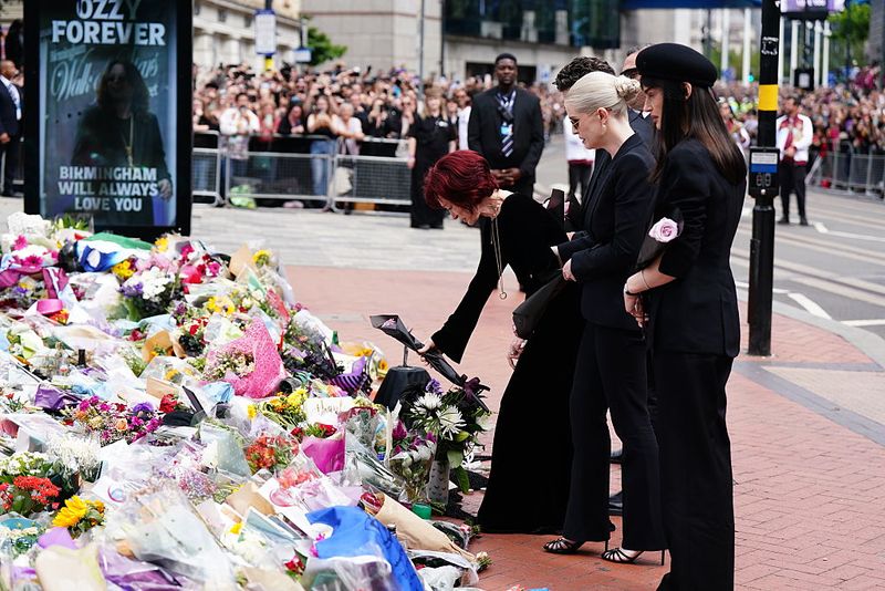 The family of Ozzy Osbourne (left to right) Jack Osbourne, Sharon Osbourne and Kelly Osbourne lay flowers and view the messages and floral tributes left at the Black Sabbath Bridge bench on Broad Street in Birmingham in memory of Black Sabbath frontman Ozzy Osbourne, as his body is brought back to his home city for a procession following his death last week aged 76. Picture date: Wednesday July 30, 2025. (Photo by Jacob King/PA Images via Getty Images)