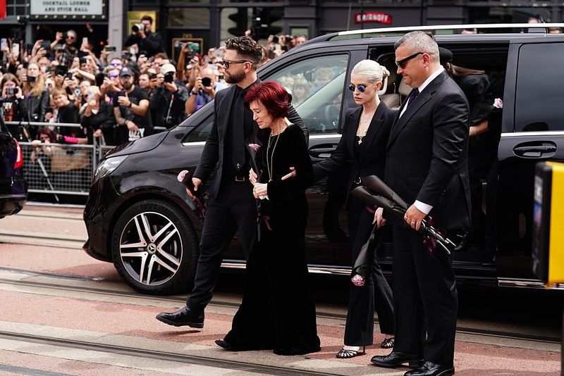 The family of Ozzy Osbourne (left to right) Jack Osbourne, Sharon Osbourne and Kelly Osbourne lay flowers and view the messages and floral tributes left at the Black Sabbath Bridge bench on Broad Street in Birmingham in memory of Black Sabbath frontman Ozzy Osbourne, as his body is brought back to his home city for a procession following his death last week aged 76. Picture date: Wednesday July 30, 2025. (Photo by Jacob King/PA Images via Getty Images)