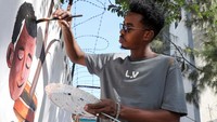 Pada sebuah pameran baru-baru ini, warga setempat berhenti sejenak untuk mengagumi lukisan-lukisan tersebut, yang banyak di antaranya mencerminkan harapan pribadi para seniman mahasiswa akan perdamaian, identitas, dan rasa memiliki di negara yang masih dalam proses pemulihan dari konflik selama puluhan tahun. Foto: REUTERS/Feisal Omar