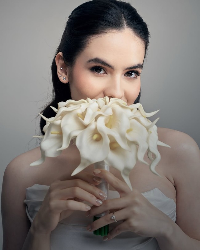 Steffi terlihat menggenggam buket bunga Calla Lily putih—bunga dengan bentuk terompet yang dikenal melambangkan keanggunan dan kemurnian. Pemilihan buket tunggal ini menguatkan kesan modern yang clean dan sophisticated. Foto: Instagram/@steffizamoraaa