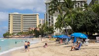 Pantai Waikiki, yang sempat sepi selama beberapa jam, kembali dipenuhi pengunjung yang menikmati sinar matahari dan bermain di tepi laut. Beberapa dari mereka sempat mengungsi ke tempat yang lebih tinggi sebelum otoritas memberi lampu hijau. (REUTERS/Marco Garcia)  