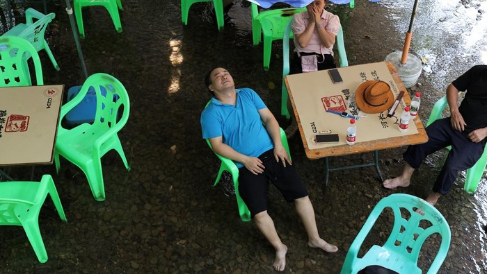 Bermain Mahjong di Sungai, Cara Unik Warga Chongqing Hadapi Gelombang Panas People play Mahjong on a shallow river amid a red alert for heat at Pianyan ancient town in Chongqing, China August 1, 2025. REUTERS/Go Nakamura