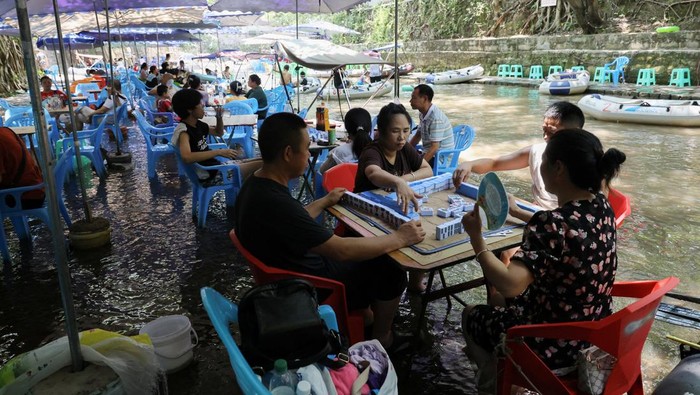 People play Mahjong on a shallow river amid a red alert for heat at Pianyan ancient town in Chongqing, China August 1, 2025. REUTERS/Go Nakamura