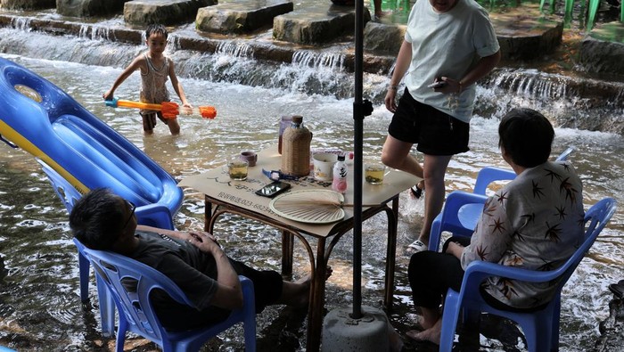 Bermain Mahjong di Sungai, Cara Unik Warga Chongqing Hadapi Gelombang Panas People play Mahjong on a shallow river amid a red alert for heat at Pianyan ancient town in Chongqing, China August 1, 2025. REUTERS/Go Nakamura