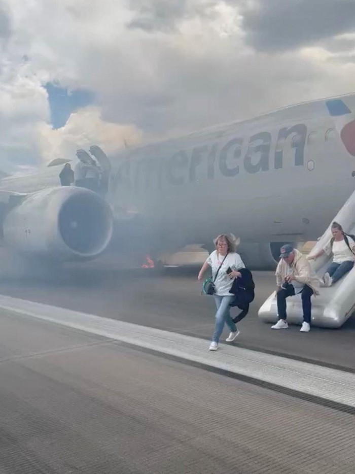Passengers evacuate an American Airlines plane by an emergency slide as a fire burns and smoke emits from the aircraft, at the Denver International Airport, Denver, Colorado, U.S. July 26, 2025, in this screengrab obtained from a social media video. @highlymigratoryfishing via Instagram/via REUTERS  THIS IMAGE HAS BEEN SUPPLIED BY A THIRD PARTY. MANDATORY CREDIT. NO RESALES. NO ARCHIVES.  VERIFICATION LINES -  Location was verified by the runway outline that matched the one from the Denver International Airport satellite imagery. The date when the videos were filmed was verified by original file metadata.