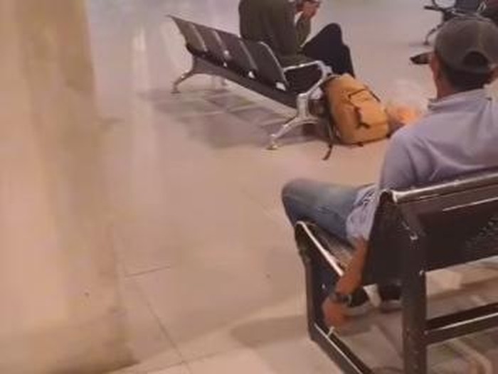 Tangkapan layar seorang pria bertopi merokok di area dilarang di pintu kedatangan Bandara Sultan Hasanuddin Makassar.