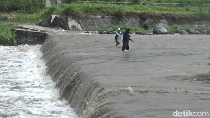 Warga menyebrangi derasnya arus banjir lahar di Sungai Regoyo