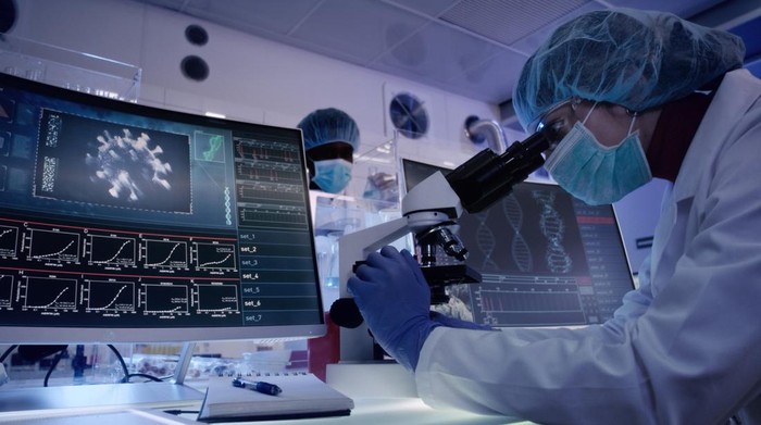 Female microbiologist studying coronavirus with microscope. Fighting with pandemic, Looking through microscope