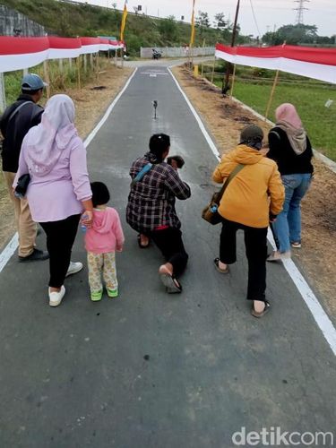 Warga saat berfoto di samping bendera Merah Putih sepanjang 800 meter yang terpasang di Desa Tarubasan, Kecamatan Karanganom, Klaten, Sabtu (2/8/2025).