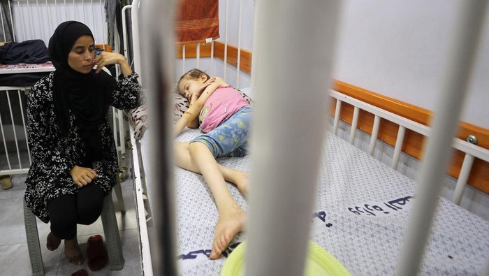 A Palestinian girl Jana Ayad, who is malnourished, according to medics, lies on a bed as her mother, Nasma Ayad, sits beside her, holding her hand, as she receives treatment at a hospital in Gaza City, amid a worsening hunger crisis, July 29, 2025. REUTERS/Mahmoud Issa