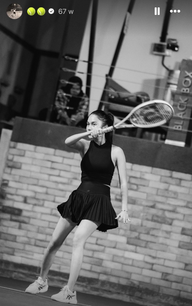 Dalam potret hitam-putih yang lebih dramatis, Azizah mengenakan outfit serba hitam, kali ini berupa tank top high neck tanpa lengan dipadukan dengan rok plisket. Outfit ini menonjolkan siluet atletis namun tetap anggun. Penampilan tersebut dilengkapi dengan sepatu putih dengan logo hitam. Foto: Instagram/@azizahsalsha_