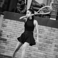 Dalam potret hitam-putih yang lebih dramatis, Azizah mengenakan outfit serba hitam, kali ini berupa tank top high neck tanpa lengan dipadukan dengan rok plisket. Outfit ini menonjolkan siluet atletis namun tetap anggun. Penampilan tersebut dilengkapi dengan sepatu putih dengan logo hitam. Foto: Instagram/@azizahsalsha_