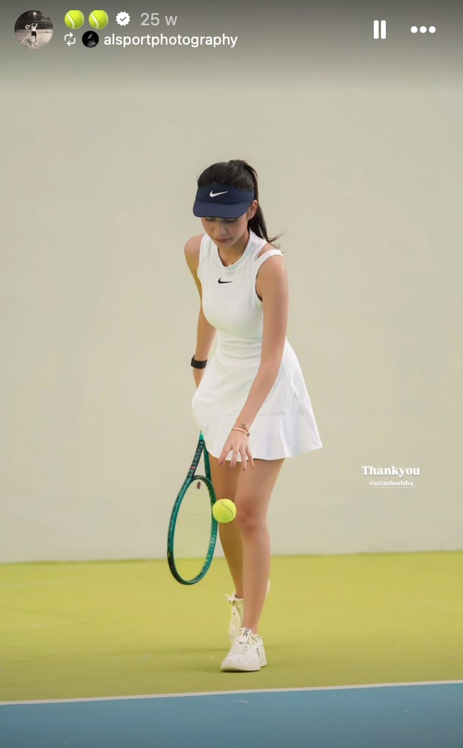 Penampilan ini terlihat klasik dan ikonik ala pemain tenis profesional. Azizah memakai dress tenis putih tanpa lengan dengan model high neck dan detail cut-out di bagian bahu kiri, memberikan sentuhan modern. Ia juga memakai visor hitam dan wristband senada di tangan kanan. Foto: Instagram/@azizahsalsha_