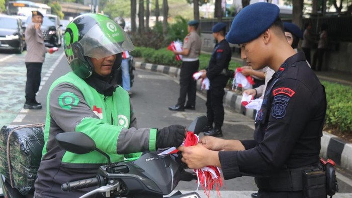Brimob Polda Metro Jaya turun membagikan ribuan bendera Merah Putih ke pengendara menyambut HUT ke-80 RI, Senin (4/8/2025).
