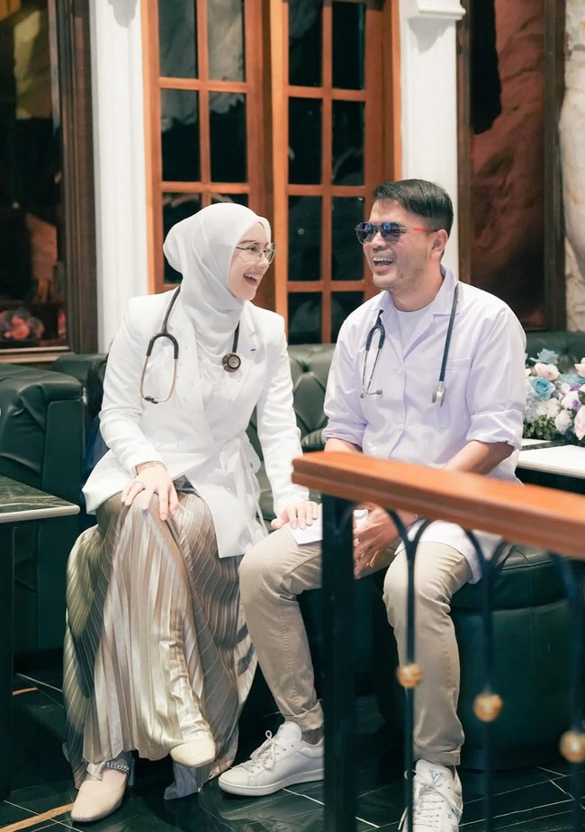 Penampilan Irish senada dengan sang suami, Haldy Sabri yang juga memilih busana bernuansa putih dan coklat. Haldy juga tampak mengalungkan stetoskop di lehernya. Foto: Instagram/@_irishbella_