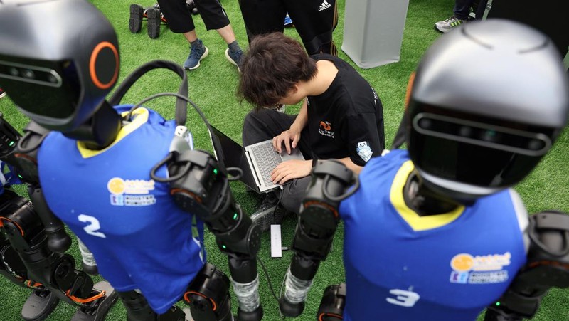 T1 humanoid robots developed by Booster Robotics in action on a football pitch, during a practice in preparation for soccer competitions at the inaugural World Humanoid Robot Games, at the National Speed Skating Oval in Beijing, China August 1, 2025. REUTERS/Florence Lo