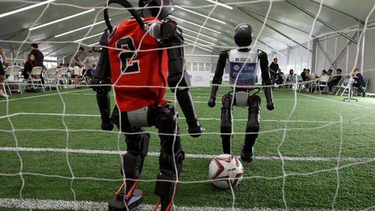 T1 humanoid robots developed by Booster Robotics in action on a football pitch, during a practice in preparation for soccer competitions at the inaugural World Humanoid Robot Games, at the National Speed Skating Oval in Beijing, China August 1, 2025. REUTERS/Florence Lo