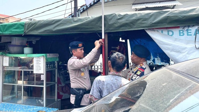 Satuan Brimob Polda Metro membagikan bendera Merah Putih di rumah warga jelang peringatan HUT ke-80 RI. (dok istimewa)