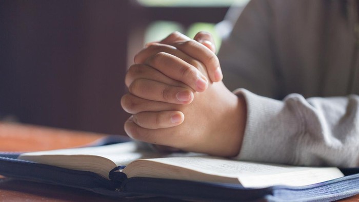 Hands folded in prayer on a Holy Bible  in church concept for faith, spirtuality and religion, Worship, sins and prayer.