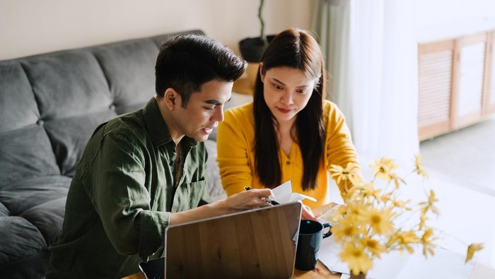 Asian husband and wife planning family finances together at home.