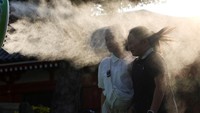Para pengunjung beristirahat di dekat kabut dingin di Kuil Sensoji. Sejauh musim panas ini, lebih dari 53.000 orang telah dibawa ke rumah sakit karena sengatan panas, menurut Badan Penanggulangan Bencana dan Kebakaran. REUTERS/Issei Kato