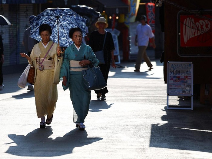 Visitors holding parasols walk along Nakamise street at the Asakusa district, a popular sightseeing spot, as the Japanese government issued a heatstroke alert in Tokyo and other prefectures due to a heatwave, in Tokyo, Japan August 5, 2025.  REUTERS/