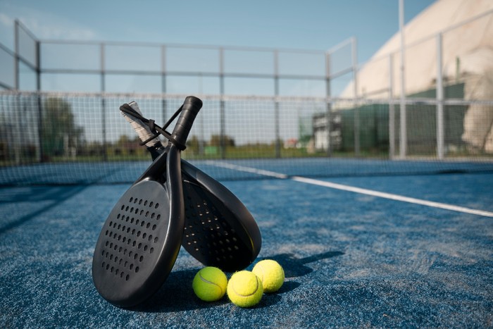Raket padel dan bola tenis di lapangan padel