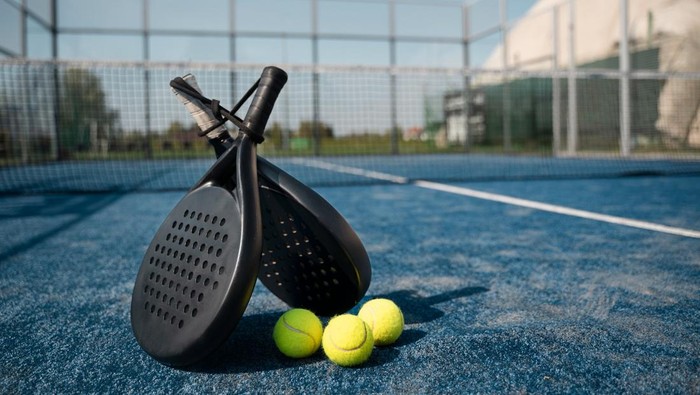 Raket padel dan bola tenis di lapangan padel