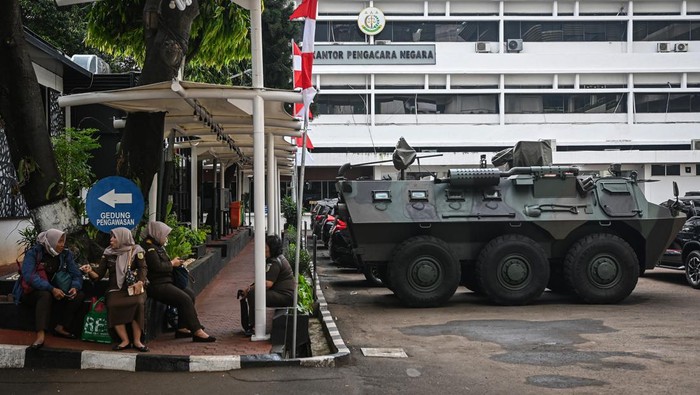 Penampakan Dua Panser Anoa TNI Siaga di Kejagung Pegawai melintas di dekat kendaraan taktis Panser Anoa 6x6 milik TNI yang terparkir di Kejaksaan Agung, Jakarta, Selasa (5/8/2025). Kepala Pusat Penerangan Hukum Kejaksaan Agung, Anang Supriatna menjelaskan bahwa kehadiran dua kendaraan militer tersebut berkaitan dengan pengamanan rutin sekretariat Satuan Tugas (Satgas) Penertiban Kawasan Hutan (PKH) yang sesuai dengan Peraturan Presiden Nomor 66 Tahun 2025 tentang Perlindungan Negara Terhadap Jaksa Dalam Melaksanakan Tugas dan Fungsi Kejaksaan Republik Indonesia. ANTARA FOTO/Sulthony Hasanuddin/bar