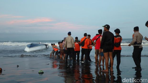 Petugas SAR Denpasar, polisi, dan warga berjibaku membalikkan badan kapal yang masih terbalik di bibir Pantai Matahari Terbit, Selasa (5/8/2025). (Aryo Mahendro)