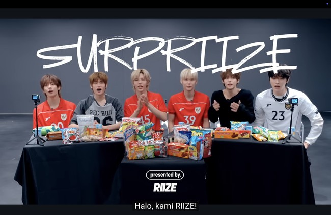 Grup KPop RIIZE mengejutkan penggemar dengan penampilannya memakai jersey timnas Indonesia. Dalam konten YouTube terbaru, para personel RIIZE memperkenalkan camilan favorit mereka dari Indonesia dan Thailand. Foto: dok. YouTube RIIZE