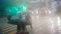 Pejalan kaki berjalan melewati area yang terendam banjir saat hujan deras mengguyur Hong Kong, Selasa (5/8/2025). Petir menyambar langit gelap Hong Kong menciptakan kilatan dramatis di tengah hujan deras yang membanjiri kota. Foto: REUTERS/Lam Yik