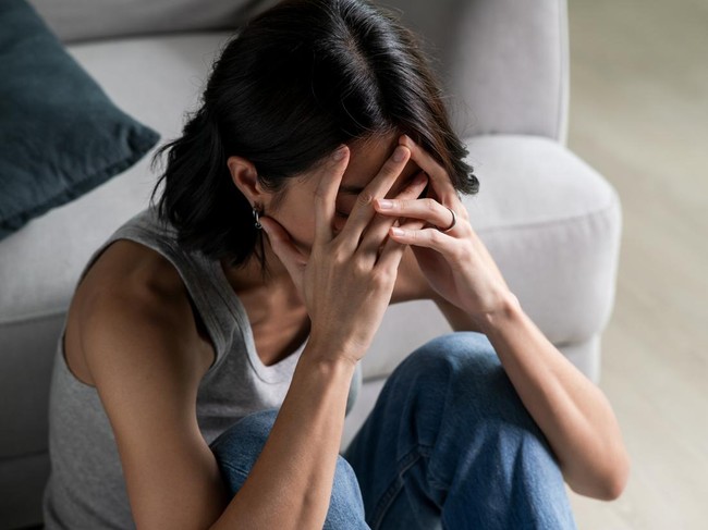 Young Asian woman sitting on floor feeling sad tired and worried suffering depression in mental health.
