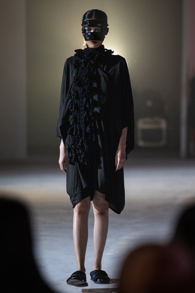 Dengan 34 look yang ditampilkan secara intens di panggung berasap dan pencahayaan merah kelam, koleksi ini menghadirkan atmosfer teatrikal yang kuat. Setiap model melangkah tenang mengenakan topeng hitam berhias payet, menyembunyikan ekspresi, dan menyerahkan narasi sepenuhnya pada potongan busana yang dikenakan. (Foto: Dok. JF3)