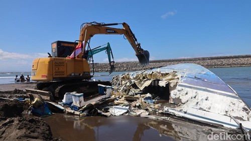 Lambung perahu Bali Dolphin Cruise II dicabik-cabik dua alat berat di bibir Pantai Sanur, Rabu (6/8/2025). (Aryo Mahendro/detikBali)