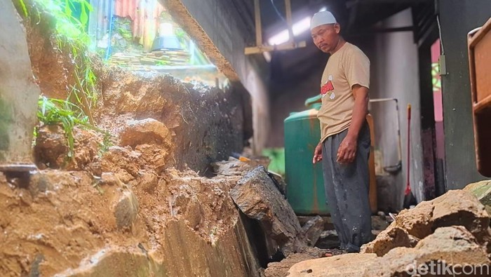 Suban saat memindahkan bongkahan tanah padat di belakang dinding rumah yang jebol di Tarakan.
