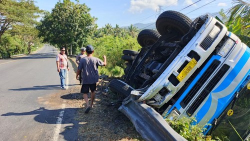 Truk tronton terbalik akibat patah as panjang di Jalan Nasional Denpasar-Gilimanuk, tepatnya di tanjakan sebelah Pos Lantas Sumbersari, Desa Melaya, Kecamatan Melaya, Kabupaten Jembrana, Rabu (6/8/2025). (Dok. Polsek Melaya)