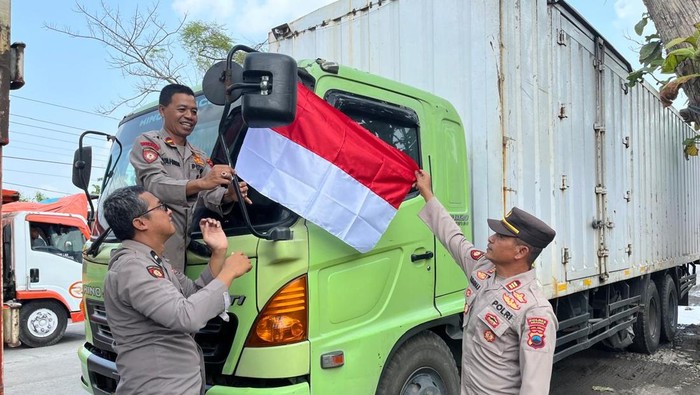 Kapolsek Sumberlawang, AKP Sudarmaji, dan jajarannya saat memasangkan bendera Merah Putih di kabin truk di Jalan Solo-Purwodadi.