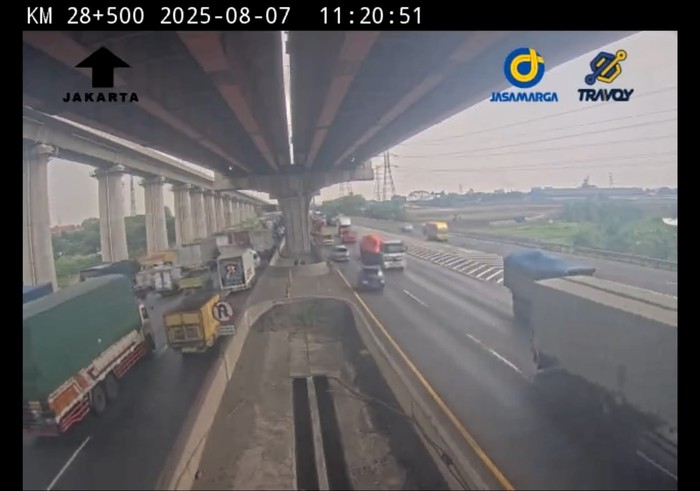 Kecelakaan truk terjadi di Tol Jakarta-Cikampek (Japek) arah Jakarta. Truk tersebut dalam kondisi terguling dan menutup dua lajur. (dok Travoy)