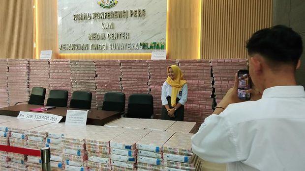 Siswa magang rebutan foto di depan uang sitaan Kejati Sumsel.