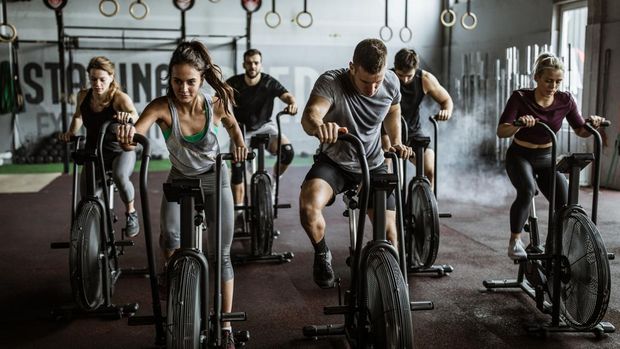 Large group of athletic people having sports training on exercise bikes in a gym