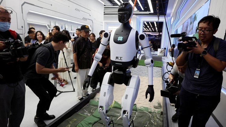 Media members work by a walking Tiangong humanoid robot during an organised media tour to Robot Mall, a store selling humanoid and other robots, in Beijing, China August 6, 2025. REUTERS/Florence Lo TPX IMAGES OF THE DAY